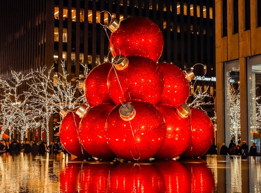 Giant red Christmas ornaments in a festive New York City setting at night.