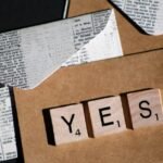 Close-up of Scrabble letters spelling YES on a vintage-style envelope for invitation or message.