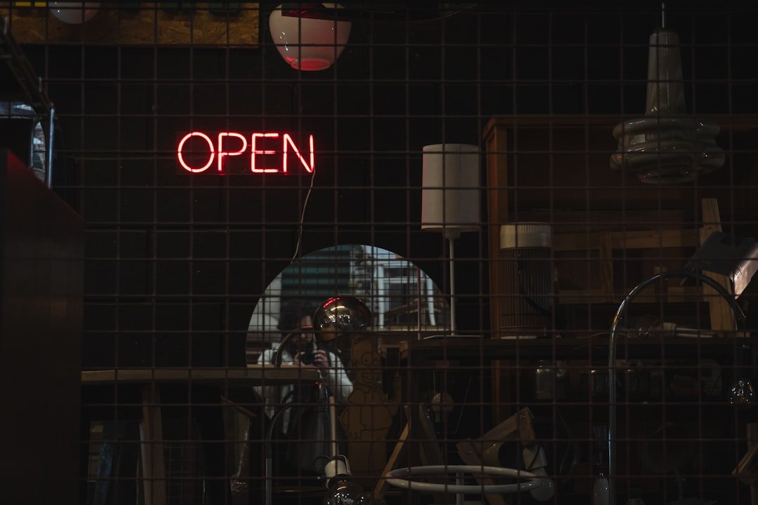 Neon open sign illuminates a dark room.