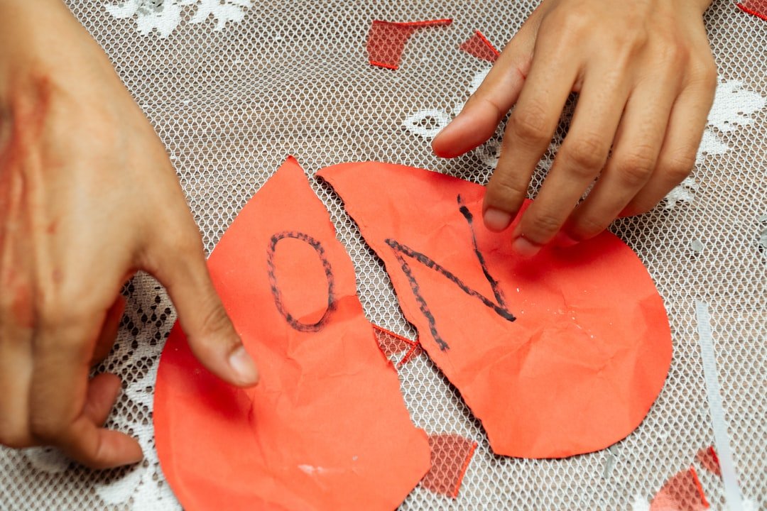 Hands arranging pieces of a broken red heart.