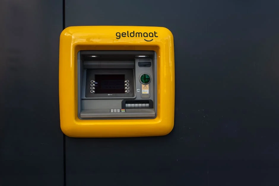 Bright yellow ATM Geldmaat machine mounted on a dark wall, offering easy cash transactions.