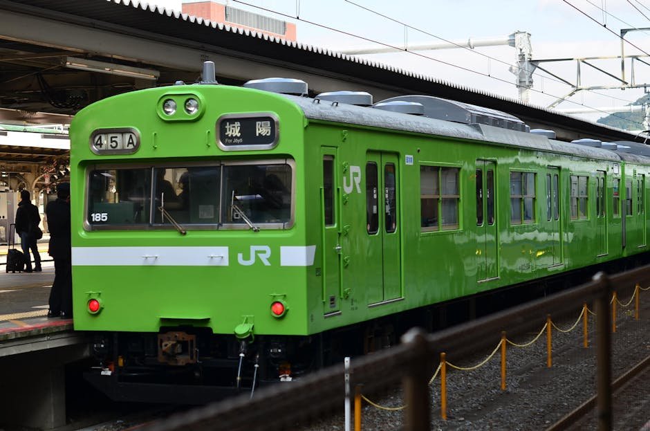 A vivid green JR train waiting at Kyoto station platform, showcasing Japan's efficient railway system.