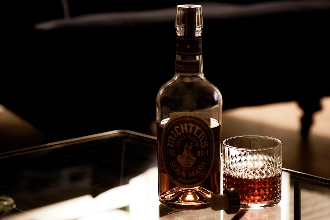 brown glass bottle beside clear drinking glass