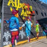 Children walk past a mural with graffiti art