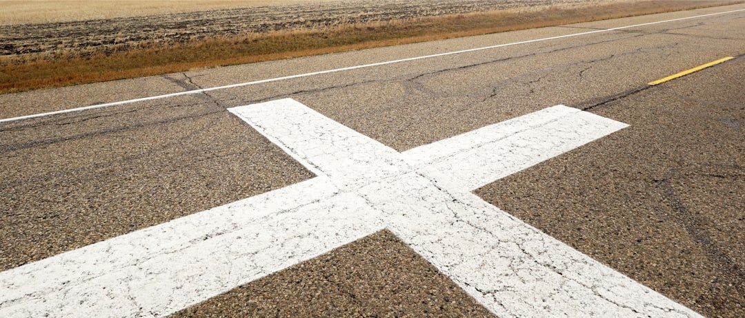 White cross marking on an asphalt road surface.