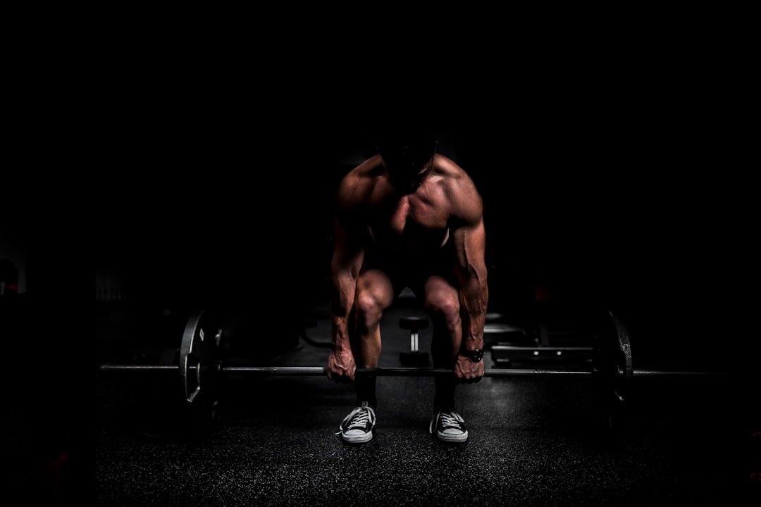 shirtless man lifting barbell in gym